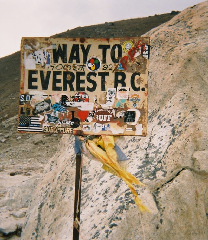 A board at Everest Base Camp filled with stickers by trekkers and climbers.
